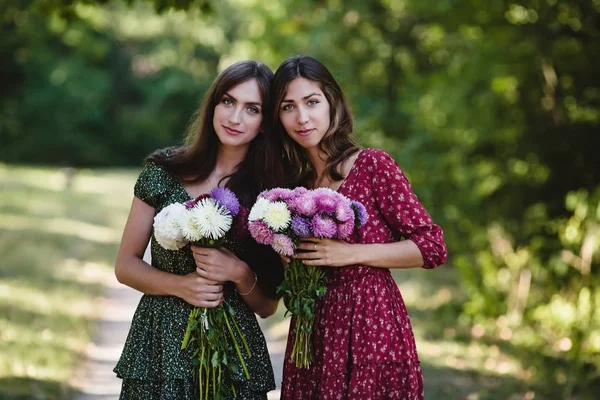 Due giovani donne sorridenti con fiori — Foto Stock