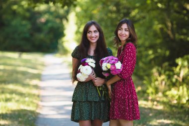 İki genç kadın çiçekler ile gülümseyen