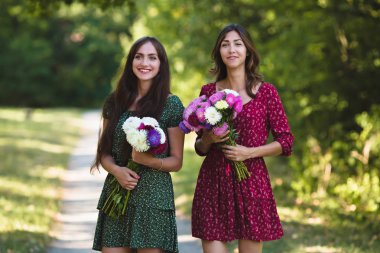 İki genç kadın çiçekler ile gülümseyen