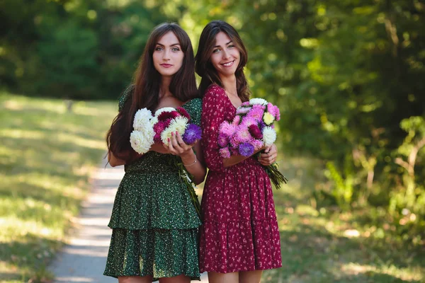 Zwei junge lächelnde Frauen mit Blumen — Stockfoto