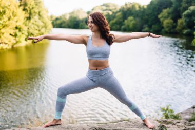 Parkta yoga egzersizi yapan güzel bir kadın.