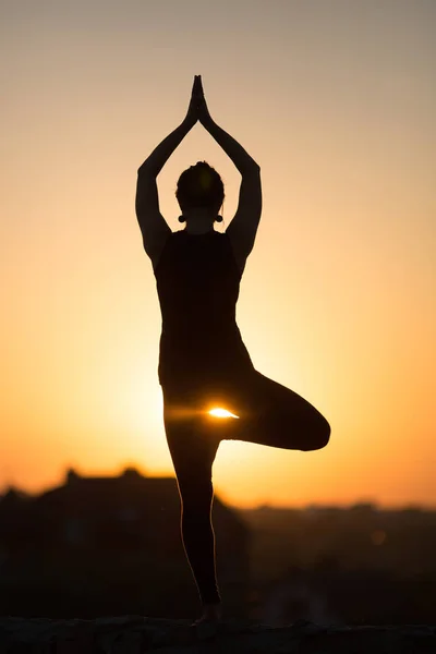 İnce kadın üzerinde turuncu güneş yoga yaparken