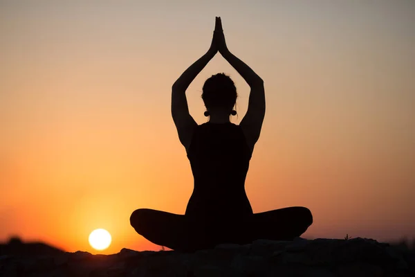 İnce kadın üzerinde turuncu güneş yoga yaparken