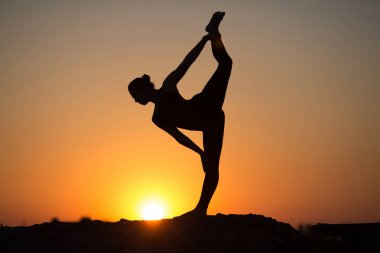 İnce kadın üzerinde turuncu güneş yoga yaparken