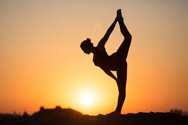 İnce kadın üzerinde turuncu güneş yoga yaparken