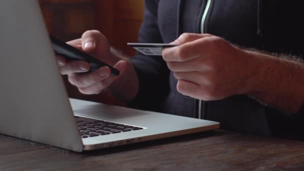 Empresario con capucha negra haciendo pago en línea con tarjeta de crédito y smartphone, compras en línea — Vídeos de Stock
