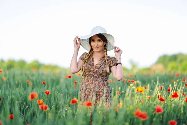 Vacker rödhårig kvinna i hatt på grönt fält med vallmo — Stockfoto