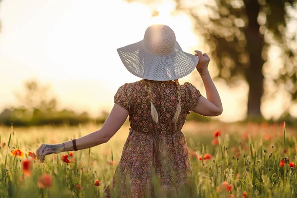 Redhead woman in hat on green field with poppies