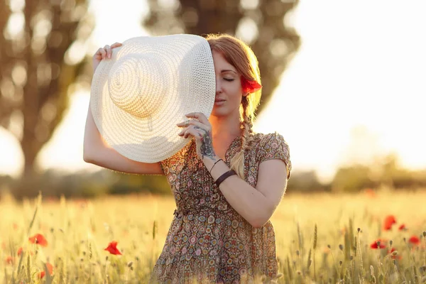 Femme rousse avec chapeau sur le champ vert avec des coquelicots — Photo