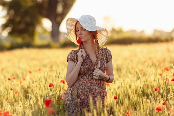 Belle rousse femme en chapeau sur champ vert avec des coquelicots — Photo