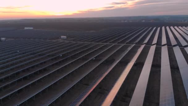 Drohnenblick in große Sonnenkollektoren auf einem Solarpark bei Sonnenuntergang. Solarzellenanlagen. Videomaterial 4k. — Stockvideo