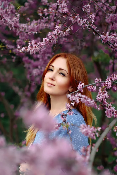 Beautiful smilling redhead woman in spring time blossom cherrytrees garden. — Stock Photo, Image