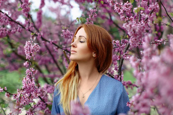 Belle femme rousse rêveuse au printemps fleur de cerisiers jardin . — Photo
