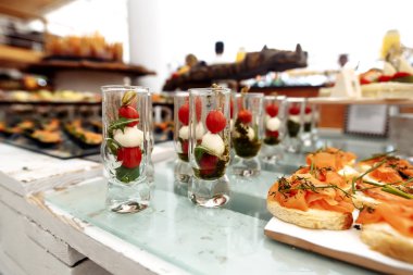 Bulanık arkaplanda pesto soslu domates ve peynirli kanepeler.