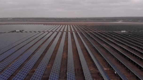 Vue aérienne d'un drone regardant vers le bas dans de grands panneaux solaires dans une ferme solaire lors d'une journée d'automne nuageuse. Centrales solaires. séquences vidéo 4k .