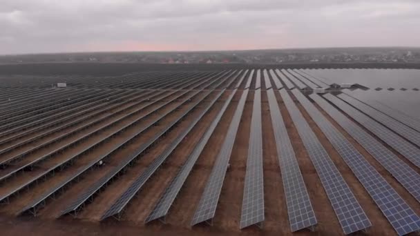 Vue aérienne d'un drone regardant vers le bas dans de grands panneaux solaires dans une ferme solaire lors d'une journée d'automne nuageuse. Centrales solaires. séquences vidéo 4k .