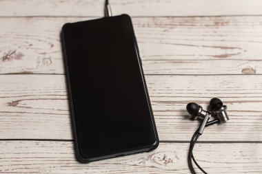 Üst görünüm akıllı telefon Model boş ekran akıllı telefon ahşap kırsal masa üzerinde kulaklık