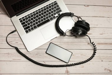Laptop, boş cep telefonu ve ahşap kırsal arka planda kulaklık. Boş akıllı telefon ekranı ve kulaklıkla. Modern kulaklıklar ve dizüstü bilgisayar işi konsepti.