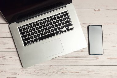 Hafif rustik ahşap masada akıllı telefonlu dizüstü bilgisayar