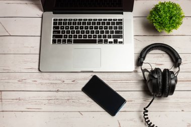 Laptop, boş cep telefonu ve ahşap kırsal arka planda kulaklık. Boş akıllı telefon ekranı ve kulaklıkla. Modern kulaklıklar ve dizüstü bilgisayar işi konsepti.