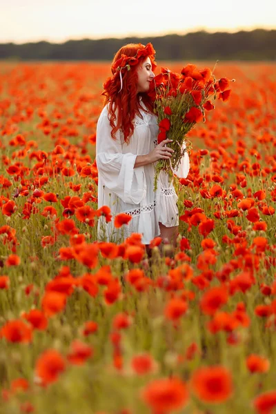 Bella rossa donna sorridente in ghirlanda su campo verde con mazzo di papaveri — Foto Stock