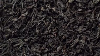 Siyah çay arkaplanından yapraklar, yakın çekim. Döndürme. Kameranın ön tarafı siyah çay ile tabağı döndürür, makro. Çin ya da Hint geleneksel çay konsepti. Gıda dokusu arka planı.