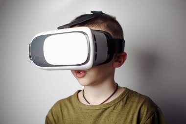 Beyaz arka planda sanal gerçeklik gözlükleriyle mobil oyun uygulaması oynayan çocuk. Oğlan hareketi ve sanal kulaklıkla kullanmak, akıllı telefonla kullanmak için video kayıt cihazı. Çağdaş teknoloji konsepti, kapat
