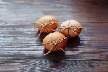 Paskalya bej yumurtaları kahverengi ahşap arka planda halatla, kopyalanmış alanla dekore edilir.