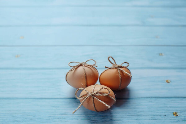 Easter beige eggs decorate with rope on blue wooden background with copyspace