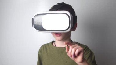 4K shot çocuk beyaz arka planda sanal gerçeklik başlığı kullanıyor. Video kayıt cihazı. Sanal gerçeklik gözlükleri. Yeni yüksek teknoloji..