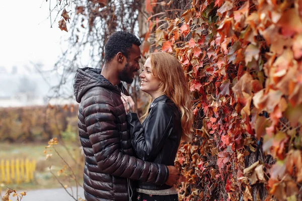 秋にポーズをとる異人種間のカップル背景 黒男と白の赤毛の女性 — ストック写真