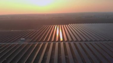 Parlak günbatımında güneş çiftliğindeki büyük güneş panellerine hava aracı görüntüsü. Güneş pili santralleri. görüntüler 4k.