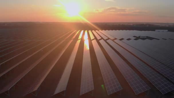 Vista aérea do drone em painéis solares grandes em uma fazenda solar no por do sol brilhante. Centrais de energia solar. imagens de vídeo 4k. — Vídeo de Stock