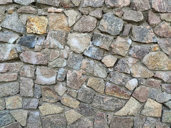 Büyük taş duvar dokusunun arka planında farklı renkte taşlar var