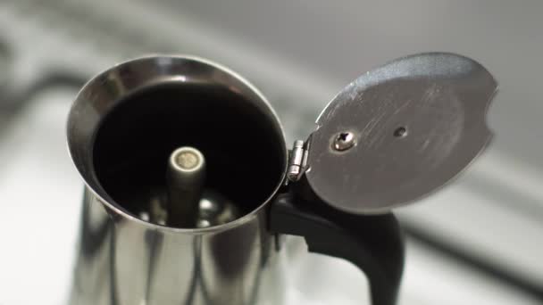 Italian coffee maker with a coffee splash. Coffee is rising and sprinkling into the pot while forming bubbles. Hand closes the Pot to avoid coffee disaster — Stock Video