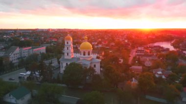 Parlak bulutlu günbatımında küçük bir kilise. Küçük Avrupa şehrinde dron tarafından çekiliyor. Kyiv bölgesi, Ukrayna.