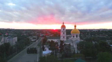 Parlak bulutlu günbatımında küçük bir kilise. Küçük Avrupa şehrinde dron tarafından çekiliyor. Kyiv bölgesi, Ukrayna.