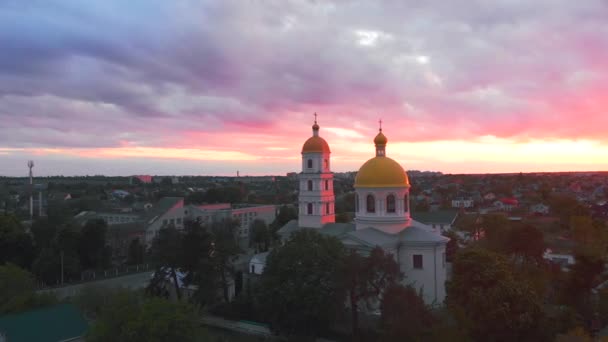 유럽의 작은 도시에서 드론 이 촬영 한 밝은 구름낀 일몰에 있는 작은 교회입니다. 우크라이나, 키예프 지역. — 비디오