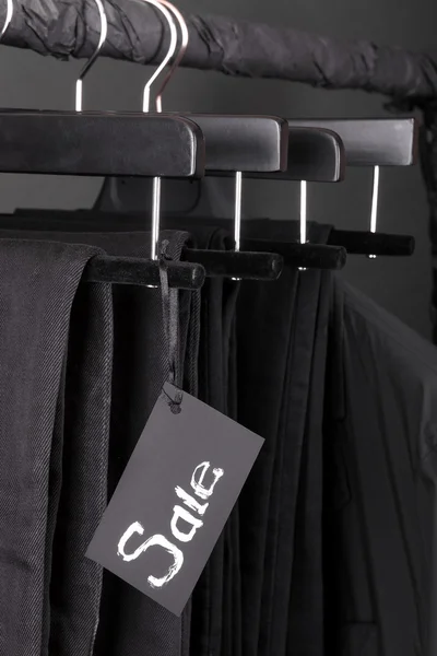 Veel zwarte broek jeans en jas opknoping op kleding rek. achtergrond. verkoop teken. vrijdag. Close-up. — Stockfoto