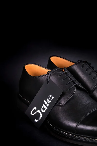 Verkaufsschild. schwarze Oxford-Schuhe auf dem Hintergrund. Rückseite. Kopierraum. Nahaufnahme. — Stockfoto