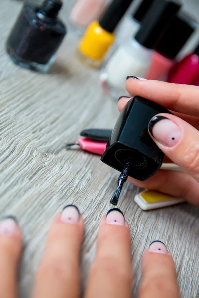 Zwarte nagellak wordt toegepast bij de hand met hulpmiddelen voor manicure op achtergrond. Mooie proces. Close-up. — Stockfoto