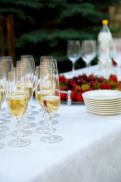 Reception table. Glasses of wine, champagne, plates and berries on the white tablecloth. Catering business. — ストック写真