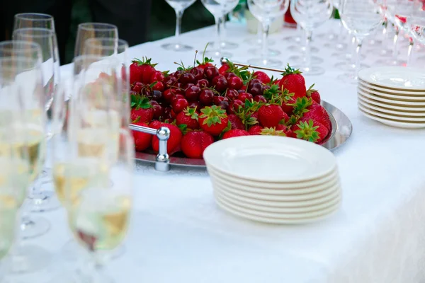 Reception table. Glasses of wine, champagne, plates and berries on the white tablecloth. Catering business. — Stock Photo, Image