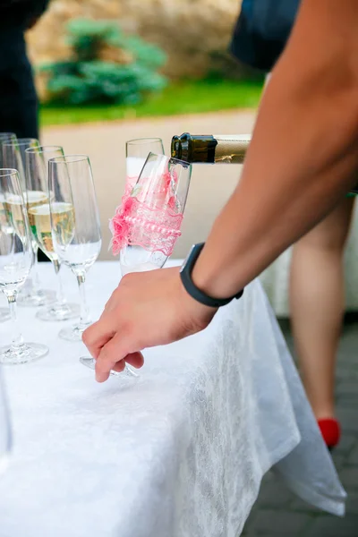 Men's hand pour champagne in wineglass. Glasses of wine, plates and berries on the white tablecloth. Catering business. Reception table. — Stock Photo, Image