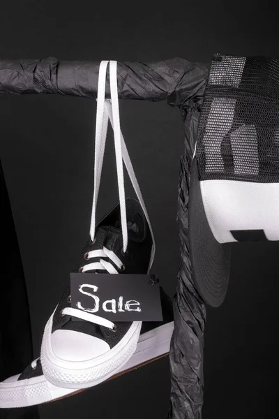 Sale sign. Black and white sneakers, cap  hanging on clothes rack   background.   friday. Close up. — Stock Photo, Image