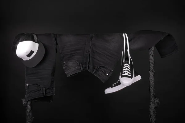 Hangende kleding. Zwart-wit sneakers, jeans van het GLB op kleding rek achtergrond. Kopiëren van ruimte. — Stockfoto