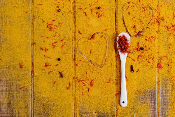 Cuore di spezie e condimenti. Cucchiaio bianco con zafferano su sfondo curry. Varie selezioni. Primo piano. Ricevuto. Amore. — Foto Stock