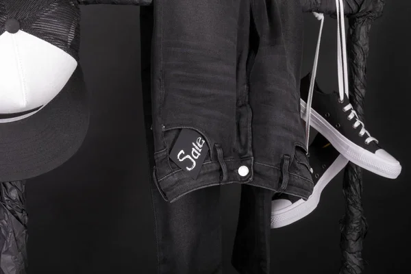 Σημάδι πώλησης. Μαύρο και άσπρο snaekers, καπάκι παντελόνι, τζιν κρέμονται σε ρούχα ράφι φόντο. Παρασκευή. Κοντινό πλάνο. — Φωτογραφία Αρχείου