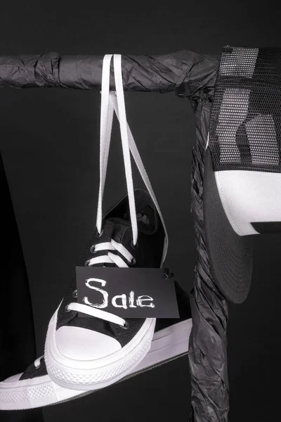 Sale sign. Black and white sneakers, cap  hanging on clothes rack   background.   friday. Close up. — Stock Photo, Image