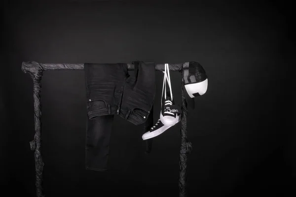 Σημάδι πώλησης. Μαύρο και άσπρο πάνινα παπούτσια, καπάκι παντελόνι, τζιν που κρέμονται στα ρούχα ράφι φόντο. Παρασκευή. Χώρο αντίγραφο. — Φωτογραφία Αρχείου